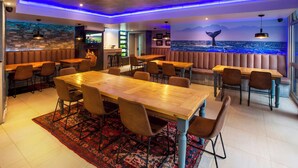 A restaurant with wooden tables and chairs, a stone wall, and a mural of a whale.