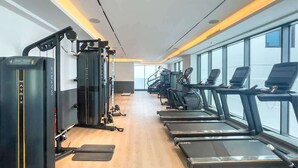 Une salle de sport équipée de tapis de course, d’une machine de musculation et d’un mur recouvert de miroirs.