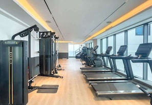 Ein Fitnessraum mit Laufbändern, Kraftgeräten und einer Spiegelwand.