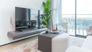 Un salon moderne doté d’un téléviseur à écran plat, d’un canapé, d’une table basse et d’une grande fenêtre offrant une vue dégagée.