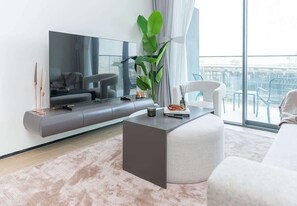 Ein modernes Wohnzimmer mit Flachbildfernseher, einer Couch, einem Couchtisch und einem großen Fenster mit Blick.