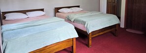 Two wooden beds with pink and green bedding, a wooden door, and a red carpet. - Mellow Breeze - Bungalow with quaint fireplace & living room in Nuwara Eliya (Seetha Eliya, Nuwara Eliya)