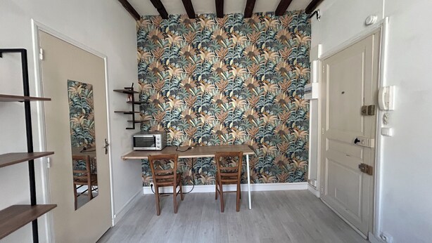 A narrow hallway with a wooden table and two chairs, a microwave, and a floral wallpaper. - Beautiful Studio T1 in Vieux tours (tours)