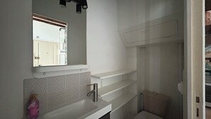 A bathroom with a white sink, mirror, and toilet. - Beautiful Studio T1 in Vieux tours (tours)