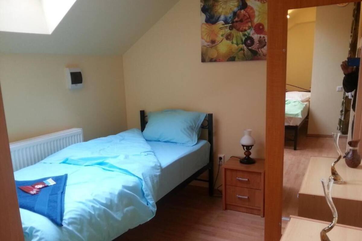 A bedroom with a bed, bedside table, and a painting on the wall.