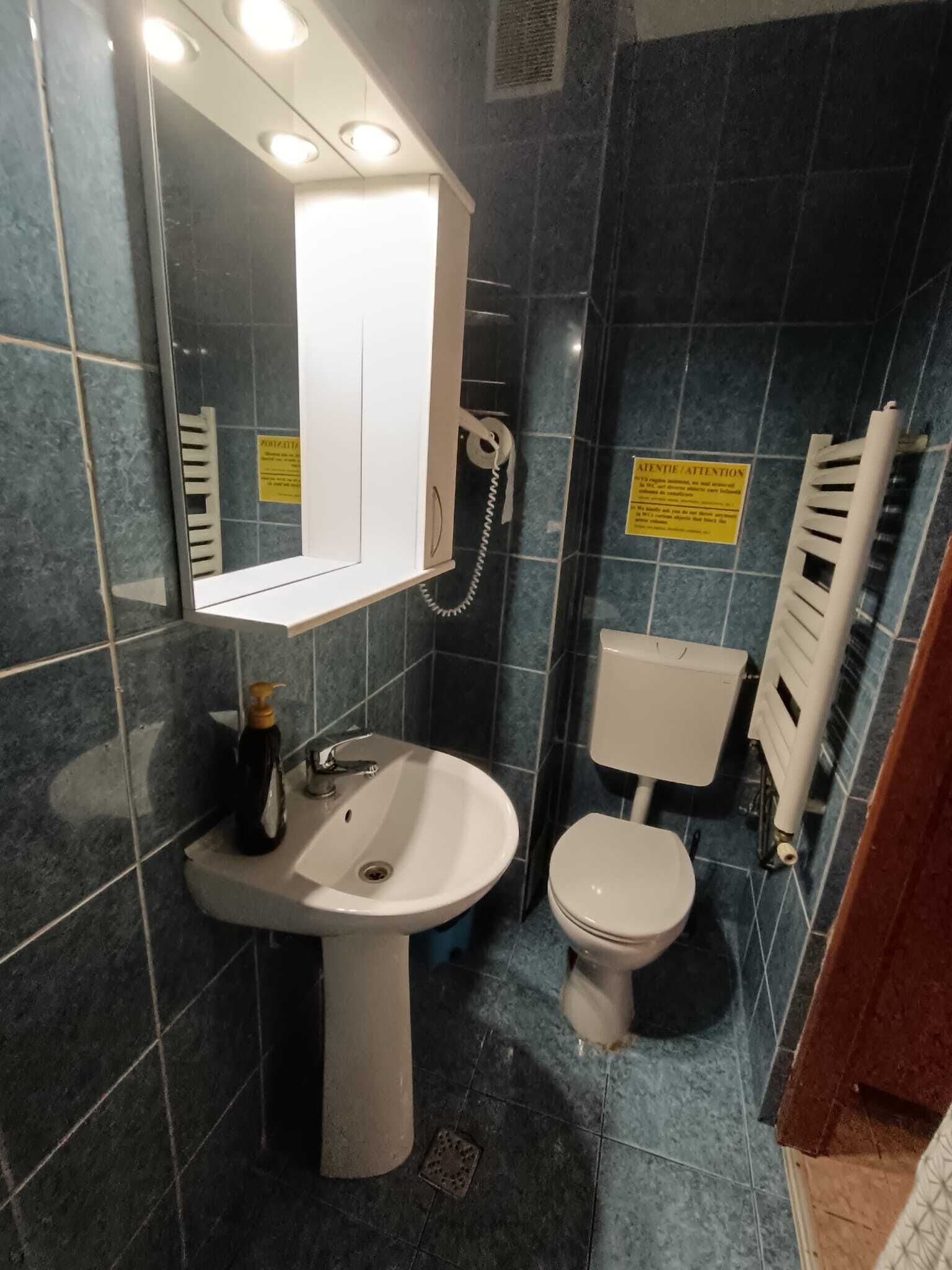 Een badkamer met een wit wastafel, toilet, spiegel en telefoon.