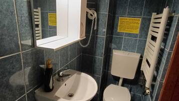 Een badkamer met een wit wastafel, toilet, spiegel en telefoon.