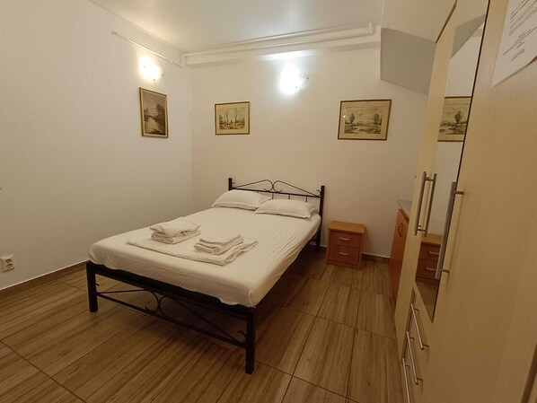 Une chambre à coucher comprenant un lit, des tables de chevet, une armoire et des œuvres d’art accrochées au mur.