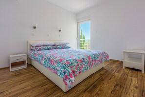 A bedroom with a bed, a nightstand, a bedside table, and a view of the outdoors. - Modern 4-star vacation apartment near the beach (Dramalj)