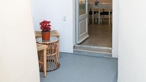 A narrow hallway with a door leading to a dining area with a table and chairs. - mati cave villas (Santorini)