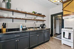 A kitchen with dark cabinets, a white stove, and a hexagonal tile backsplash. - Cozy Bungalow Near Shops-st Augustine (St. Augustine)
