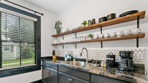 A modern kitchen with dark cabinets, a stainless steel sink, and a coffee station. - Cozy Bungalow Near Shops-st Augustine (St. Augustine)