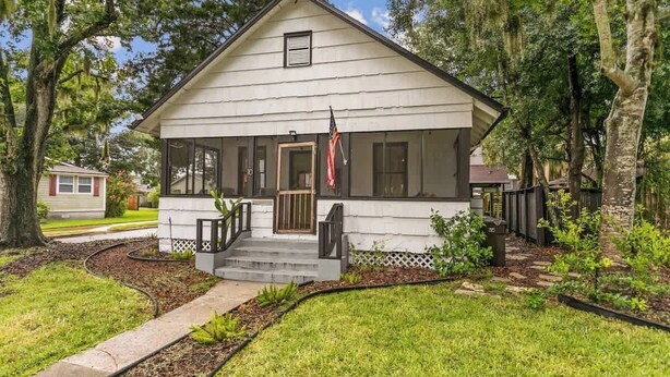 A single-story house with a porch, a front door, and an American flag. - Cozy Bungalow Near Shops-st Augustine (St. Augustine)
