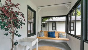 A room with a bench, a small table, a potted plant, and large windows. - Cozy Bungalow Near Shops-st Augustine (St. Augustine)
