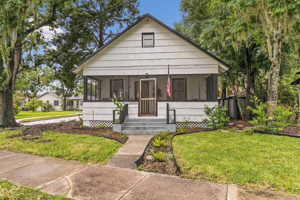 A single-story house with a front porch, a small front yard, and a flag.