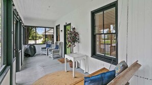 A covered porch with a bench, chairs, a small table, and a hanging swing. - Cozy Bungalow Near Shops-st Augustine (St. Augustine)