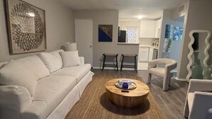 A living room with a white sofa, a round coffee table, and a kitchen in the background. - Winter Park Spacious Unit - 118 (Winter Park)