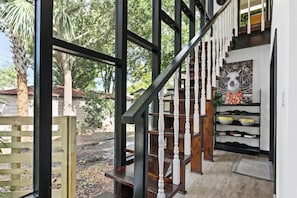 A wooden staircase with white balusters leading to a landing with a patterned wall and shelves. - Unique Pet Friendly Bungalow in St Augustine (St. Augustine)