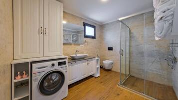 Ein modernes Badezimmer mit Waschmaschine, Waschbecken, Toilette und einer Duschkabine.