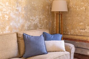 A beige sofa with two pillows, a lamp, and a textured wall. - iFlat | Charming Historic Palace Fons Trevi B15 (Rome)