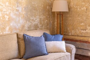 A beige sofa with two pillows, a lamp, and a textured wall. - iFlat | Charming Historic Palace Fons Trevi B15 (Rome)