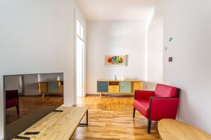 A modern living room with a wooden floor, a red sofa, a wooden coffee table, a TV, and a cabinet with drawers. - iFlat | Charming Historic Palace Fons Trevi B15 (Rome)