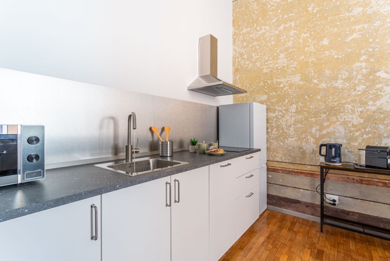 A modern kitchen with a stainless steel range hood, a built-in oven, and a granite countertop.