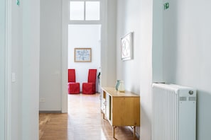 Ein Korridor mit einem Heizkörper, einem Holzschrank und roten Stühlen.