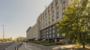 A multi-story hotel with a modern design, featuring a large entrance, outdoor seating area, and a visible restaurant. - Wolska Studio Apartments by Solarento (Warsaw)