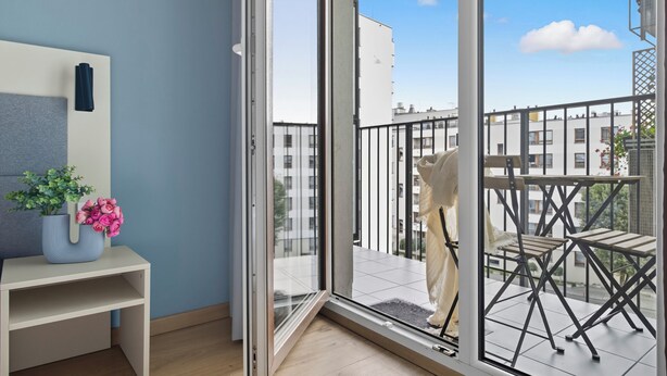 A room with a sliding glass door leading to a balcony with outdoor furniture. - Wolska Studio Apartments by Solarento (Warsaw)