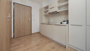 A modern kitchen with wooden flooring, white cabinets, and a built-in stove. - Wolska Studio Apartments by Solarento (Warsaw)