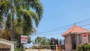 A gated entrance with a stop sign, palm trees, and a building with a red roof. - COMFORTABLE KING BEDROOM FLAT in townhome in a pleasant Hilltop neighborhood, (Kingston 6)