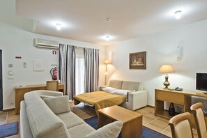 A hotel room with a bed, two sofas, a desk with a computer, a TV, and a lamp. - LAM Hotel Estarreja (Estarreja)