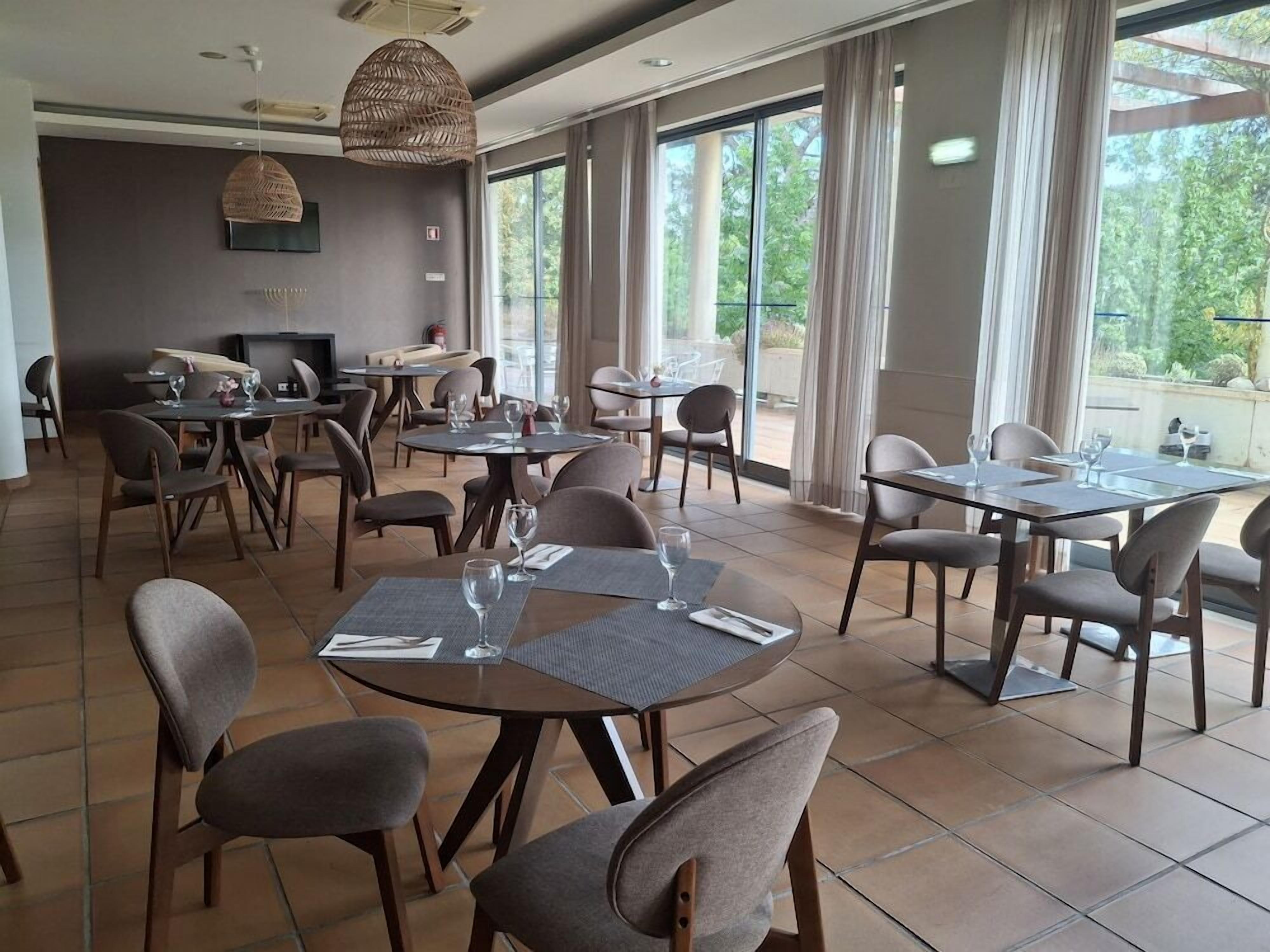 A restaurant with round tables, chairs, and hanging wicker lamps.