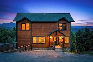 A two-story log cabin with a front porch, a stone foundation, and a view of mountains. - New Listing, Stunning Views, Private Pool, Hot Tub, Games, Free Attractions! (Gatlinburg)