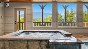 Spa-område med jacuzzi, træloft og store vinduer med udsigt til bjergene.