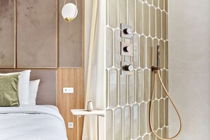 A modern hotel room with a bed, a nightstand, a wall-mounted shower with a transparent panel, and a light fixture. - Exceptional AC Apartment - Center of Paris (Paris)