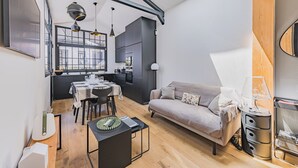 En kompakt opholdsstue med spiseplads, sofa og et lille køkken.
