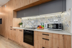 A modern kitchen with wooden cabinets, a built-in microwave, and a fruit basket on the counter. - Lumina apart near Centrum Praski Koneser (Warsaw)