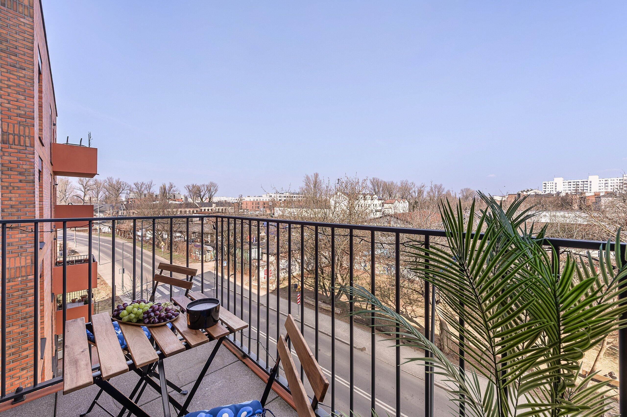 Ein Balkon mit Tisch, Stuhl und einer Topfpflanze.