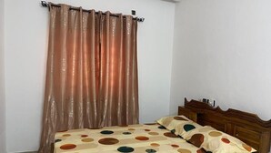 Un dormitorio con cama, cabecera de madera y cortina.