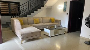 Una sala de estar con un sofá, una mesa de centro y una escalera.