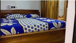 Una cama con colcha estampada, cabecero de madera y mesita de noche.