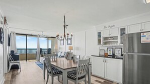 A modern kitchen with a dining area, a chandelier, and a view to the outside. - Sea Winds #502-Oceanfront Oasis with Indoor Pool! In Windy Hill - NMB! (North Myrtle Beach)