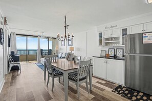 A modern kitchen with a dining area, a chandelier, and a view to the outside. - Sea Winds #502-Oceanfront Oasis with Indoor Pool! In Windy Hill - NMB! (North Myrtle Beach)