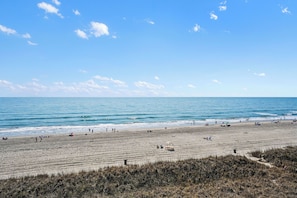 A beach with people, a clear sky, and the ocean. - Sea Winds #502-Oceanfront Oasis with Indoor Pool! In Windy Hill - NMB! (North Myrtle Beach)