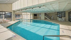 An indoor swimming pool with a clear ceiling, a staircase, and a seating area with chairs. - Sea Winds #502-Oceanfront Oasis with Indoor Pool! In Windy Hill - NMB! (North Myrtle Beach)