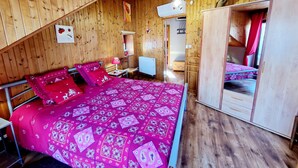 A wooden room with a bed, a dresser, and a ceiling fan.