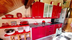 A kitchen with red cabinets, a microwave, a toaster, and a refrigerator.