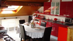 A kitchen with red cabinets, a dining table with a white tablecloth, and a red toaster.